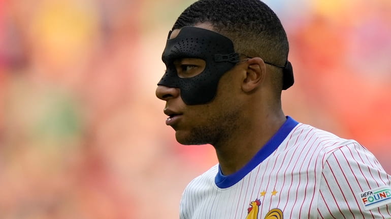 Kylian Mbappe of France wears a face mask during a...