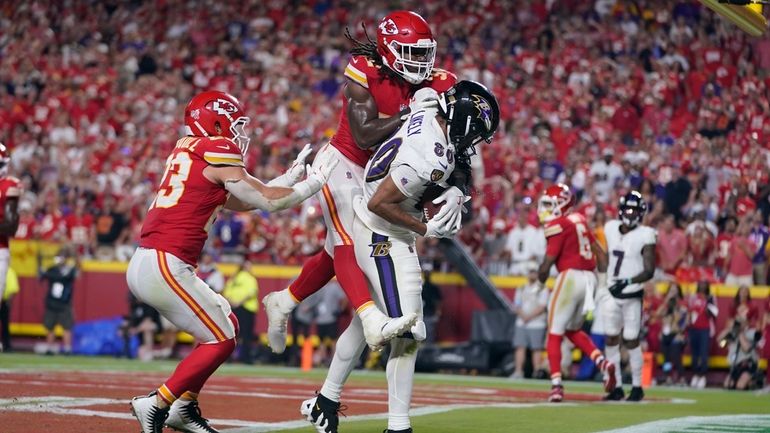 Baltimore Ravens tight end Isaiah Likely, left, catches a pass...