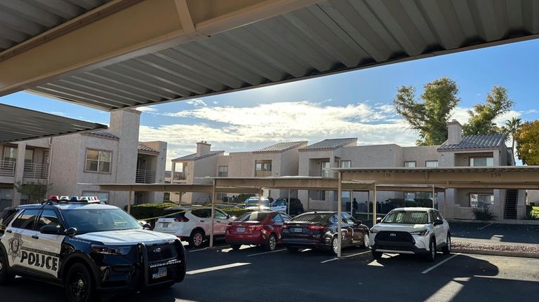 Police are stationed outside of an upstairs corner apartment, Thursday,...