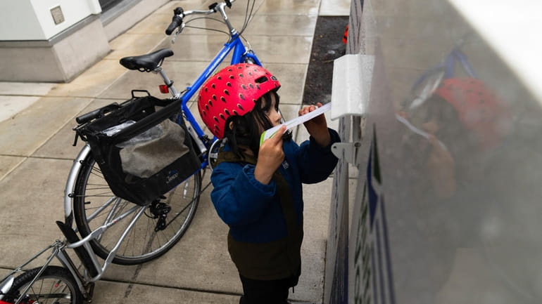 Ramona McCune, 4 1/2 years-old, puts vote-by-mail ballots into a...