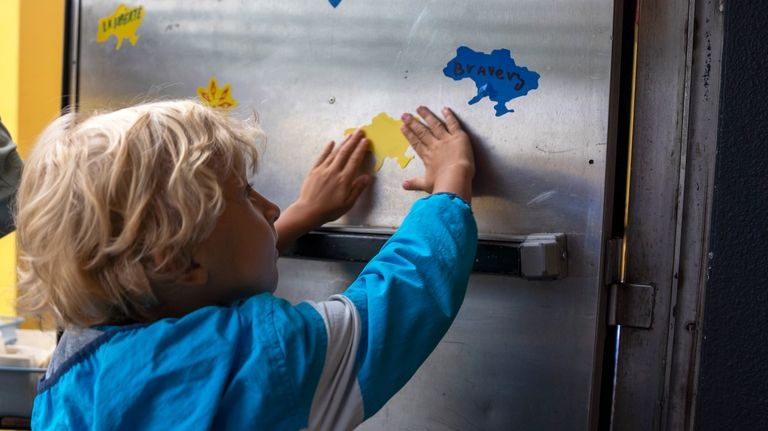 A boy pins a yellow sticker shaped like Ukraine ahead...