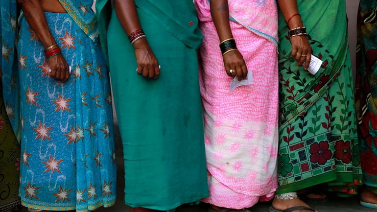 FILE- Indian women stand in a queue to cast their...