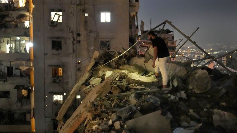 A man inspects a destroyed building that was hit by...