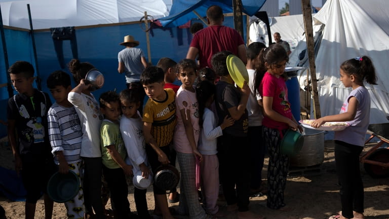 Palestinian children wait in line for a food distribution in...