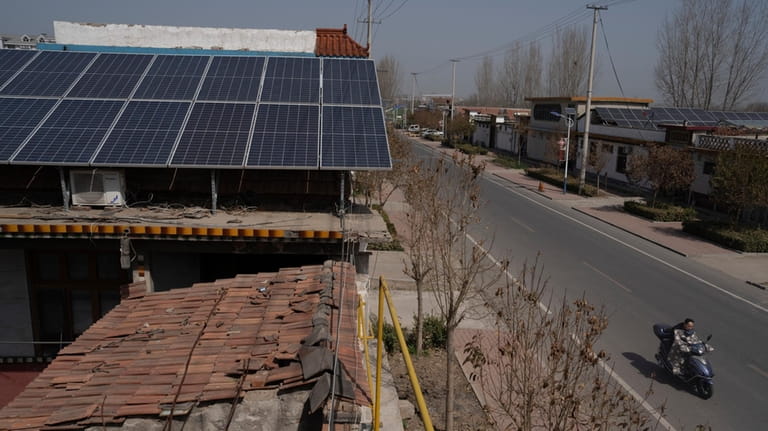 Solar panels sit on the rooftop of a house in...