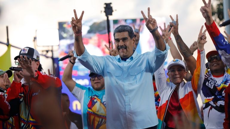 Venezuelan President Nicolas Maduro flashes victory hand signs at supporters...