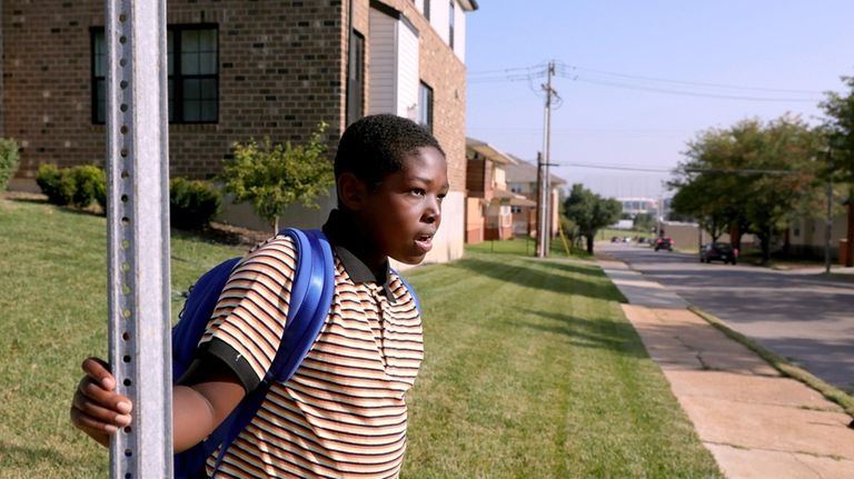 Fourth grader Shawn Baker waits for a bus to pick...