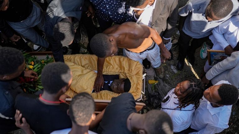 A relative pays his final respects to 16-year-old Jhon-Roselet Joseph,...