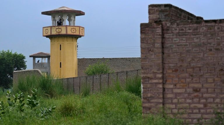 Police officers stand guard on the watch towers of district...