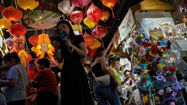 Visitors tour variety stores inside a shopping mall in Beijing...