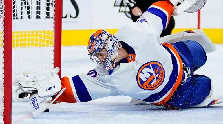 The Islanders' Semyon Varlamov reaches for a loose puck during...