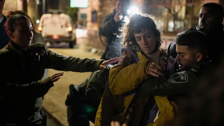 Israeli border police officers detain a woman after a march...