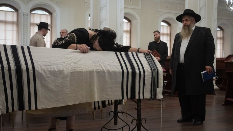 Relatives and Ukraine's chief rabbi Moshe Reuven Azman mourn at...