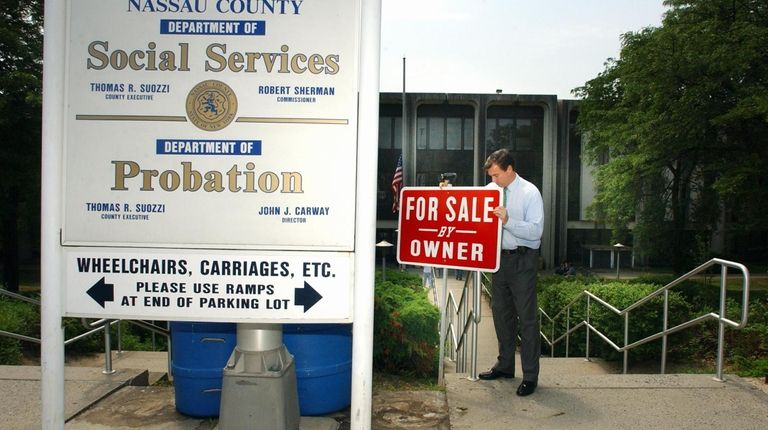 Then-Nassau County Executive Thomas Suozzi places a For Sale sign...