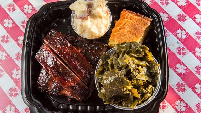 A rib platter with collard greens, garlic mashed potatoes and...