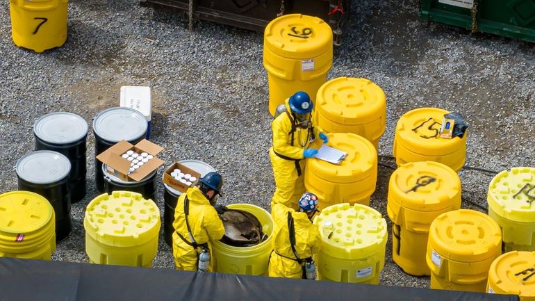 Workers on the scene with yellow containers holding 55-gallon drums...