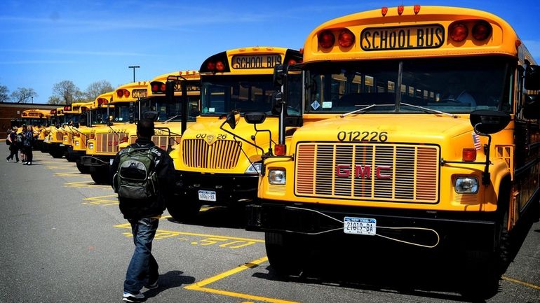 Students climb on board school buses at Longwood High School,...