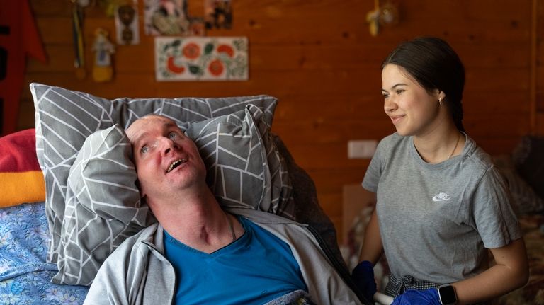 A doctor talks to Vitalii Shumei, 36, a bedridden Ukrainian...