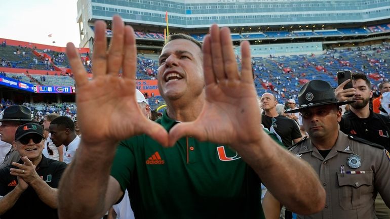 Miami head coach Mario Cristobal makes the sign of the...