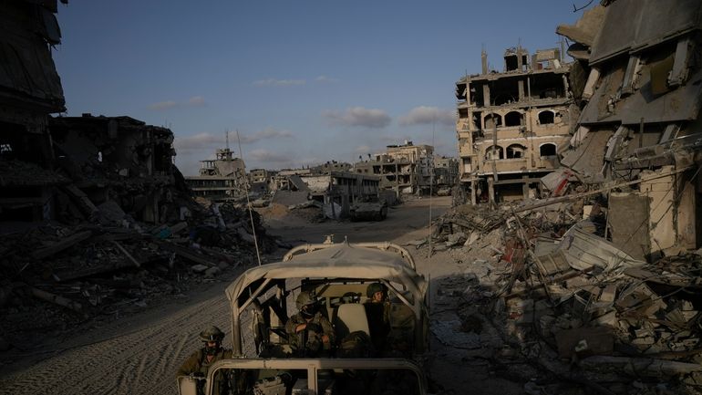 Israeli soldiers move next to destroyed buildings following Israeli strikes...