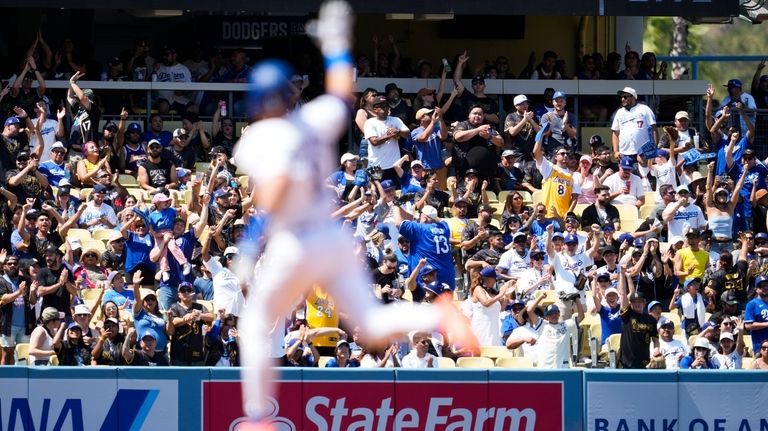 Fans reach to catch a home run ball hit by...