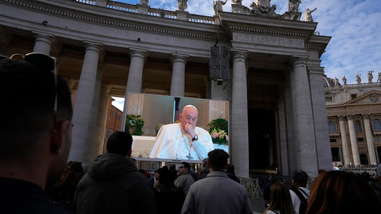 A giant screen broadcasts Pope Francis coughing during the Angelus...