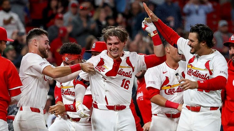 St. Louis Cardinals' Nolan Gorman, center, is mobbed by teammates...