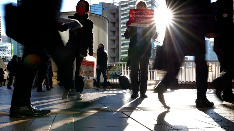 LGBTQ activists distribute chocolates to morning commuters at Shinagawa Station,...