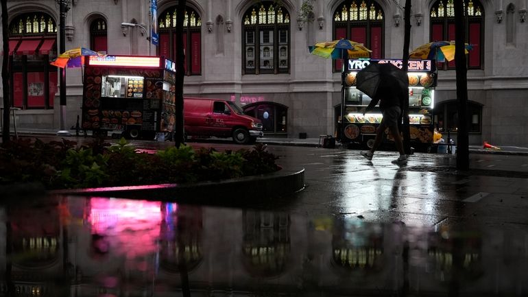 A person with an umbrella walks in the rain in...