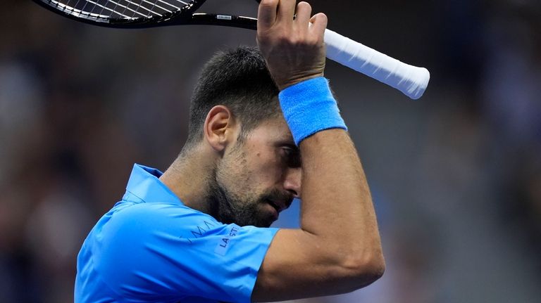 Novak Djokovic, of Serbia, wipes his face against =Alexei Popyrin,...