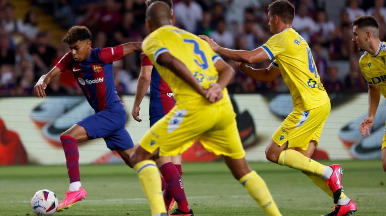 Barcelona's Lamine Yamal runs for the ball with Cadiz's Fali...