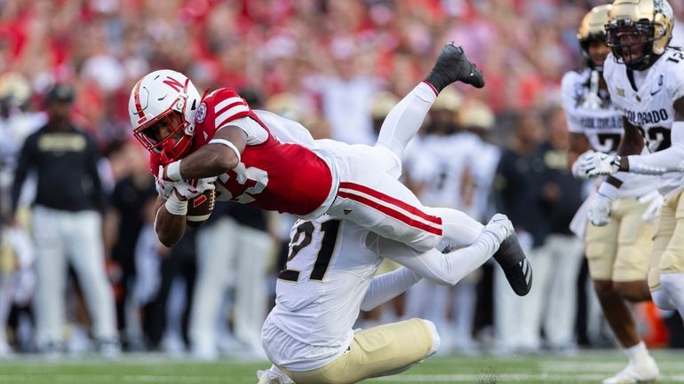 Colorado's Shilo Sanders (21) upends Nebraska's Dante Dowdell, top left,...