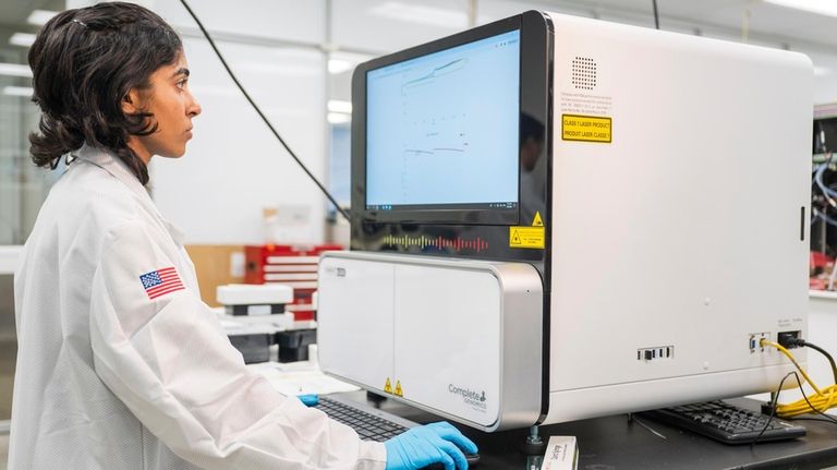 A lab technician works on a sequencer inside the quality...