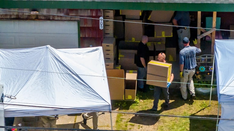 Law enforcement agents remove boxes of evidences as they search the Massapequa...