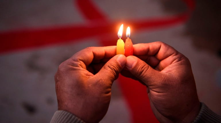 A volunteer lights candles forming the shape of a red...