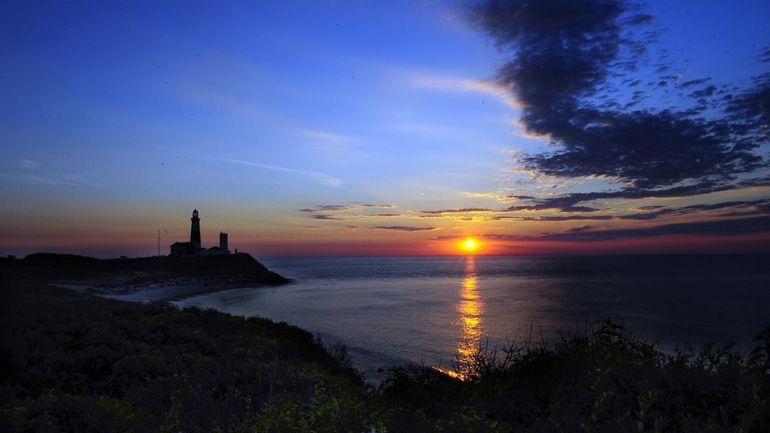 The lighthouse during sunrise at Montauk Point on the longest...