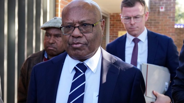 Papua New Guinea's sidelined Petroleum Minister Jimmy Maladina, center, leaves...