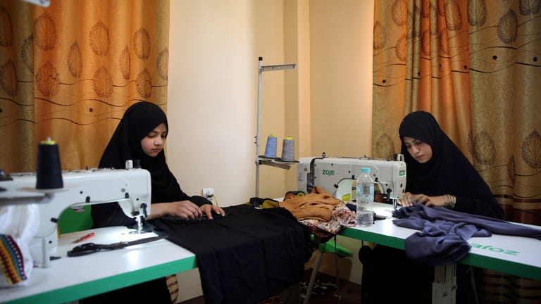 Afghan women tailors work with a sewing machine in the...