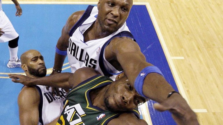 Dallas' Lamar Odom, top, reaches over Utah's Paul Millsap while...