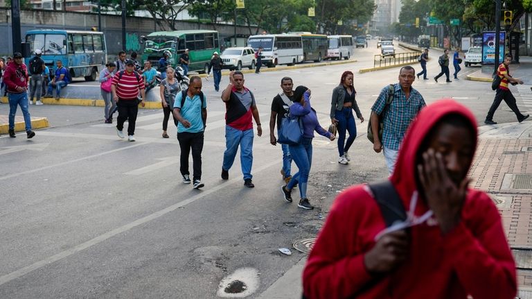 Pedestrians cross an avenue during a power outage in Caracas,...