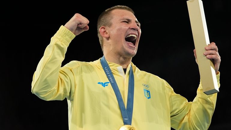 Gold medalist Ukraine's Oleksandr Khyzhniak celebrates on the podium during...