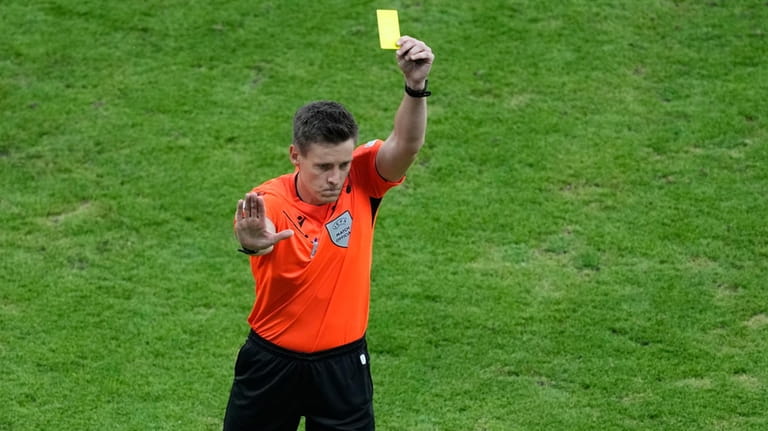 German referee Daniel Siebert shows the yellow card to Romania's...