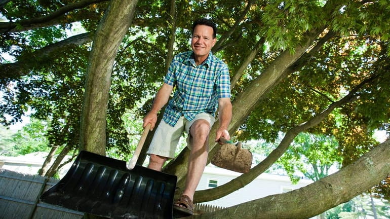 Timothy Kaler, 52, poses in a tree holding a show...