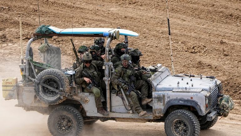 Israeli soldiers with a surfboard on the roof of their...