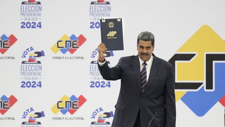 Venezuelan President Nicolas Maduro holds up his certification from the...