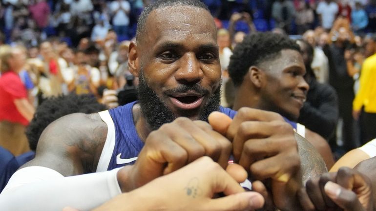 United States' forward LeBron James bumps fists with teammates after...