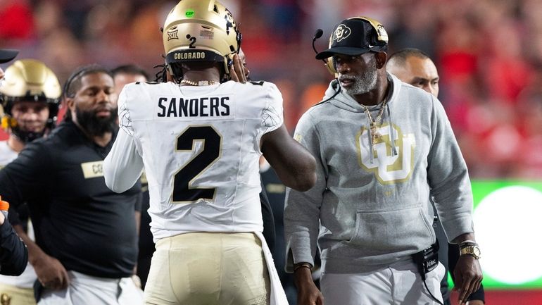 Colorado head coach Deion Sanders, right, talks with quarterback Shedeur...