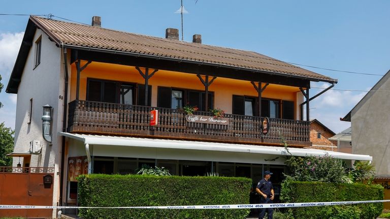 A police officer stands outside the cafe where the shooter...