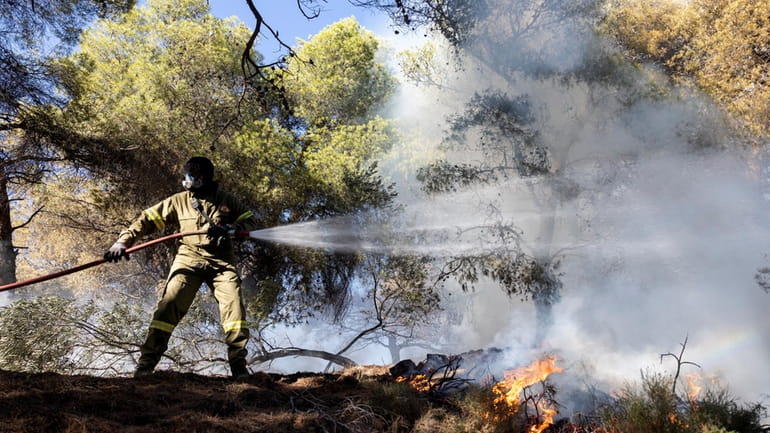 A firefighter struggles to extinguish a forest fire at Keratea...