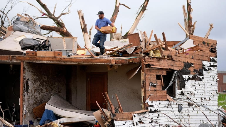 A man sorts through the remains of a home damaged...